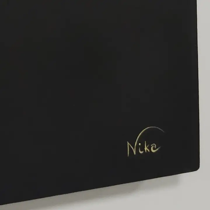 Close da assinatura Nika em dourado no canto da tela